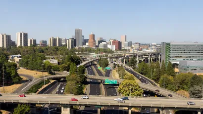 Aerial view of highway overpasses with Portland, Oregon skyline in background.