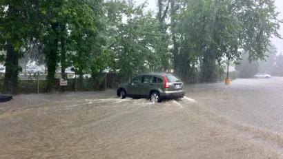 A sports utility vehicle drives throw brown floodwaters that have inundated the entire area depicted in the picture.