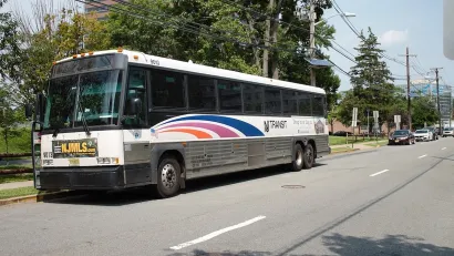 White NJ Transit parked at station with blue stripes.