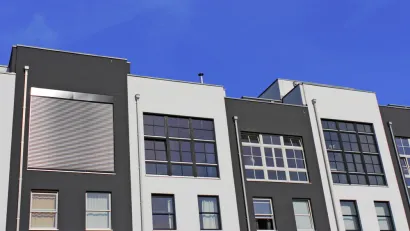 The top floors of a row of pre-fab apartments or condos are shown against a blue sky.