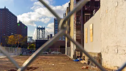 View of vacant lot in Manhattan through chain link fence