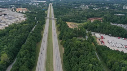 Aerial view of freeway cutting through green forest in Clayton County, Georgia