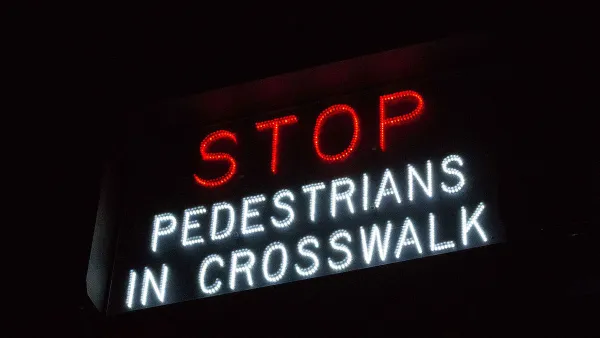 "Stop - Pedestrians in crosswalk" sign in white and red lights.