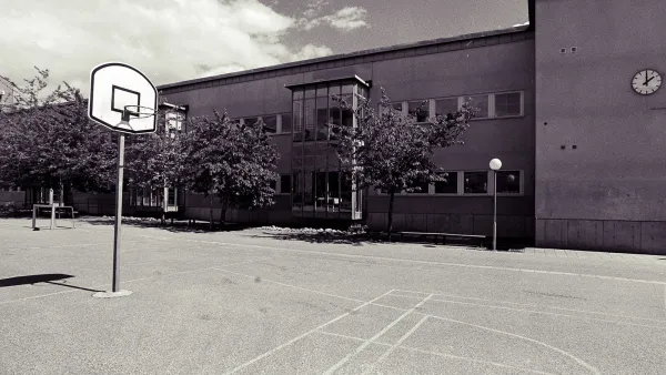 Low-saturation image of a concrete schoolyard with basketball hoop