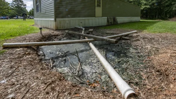 Mobile home with pipe directed into the yard into a pit of standing sewage.