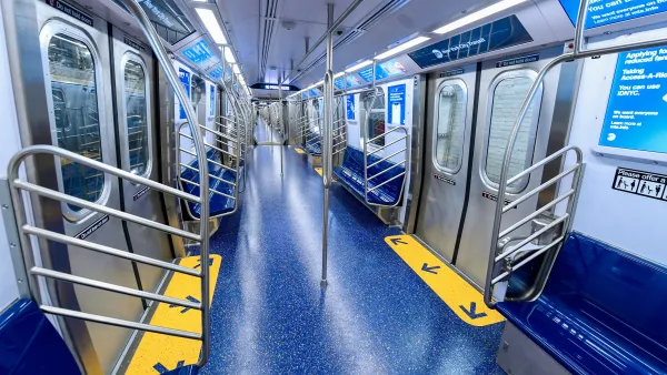 Interior of a subway car with wide doors and blue floors and seats.