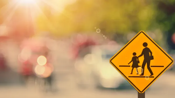 Yellow school corssing sign with two human figures against blurry background