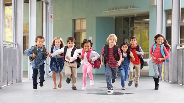 Group of elementary school children running in an outdoor corridor.