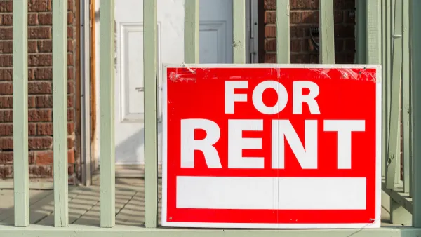 Close-up of red For Rent sign with white text on porck of brick building.