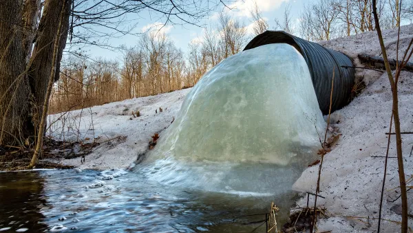 Culvert under a road in northern Wisconsin with frozen water blocking most of the pipe.