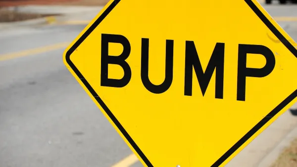Close-up on yellow sign with black 'BUMP' letters indicating speed bump ahead.