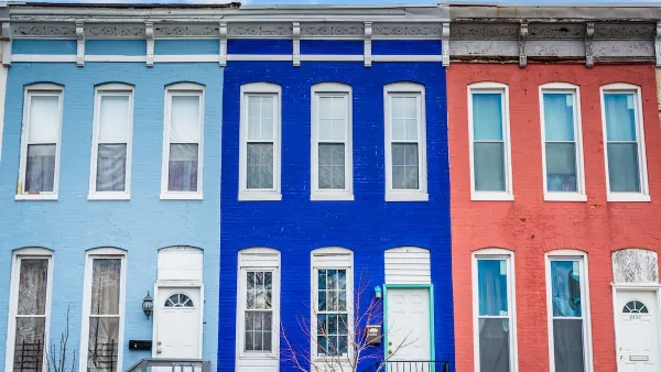 Brightly colored pale blue, dark blue, and coral row houses in Baltimore, Maryland.