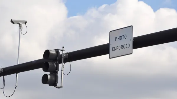 Traffic light on overhead pole with traffic camera and "Photo Enforced" sign