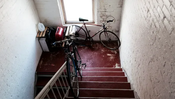 Two bicycles in apartment building stairwell landing with white painted brick walls.