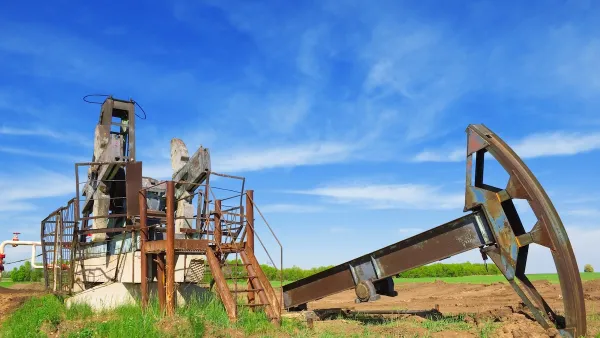 Defunct oil well disassembled in green field.