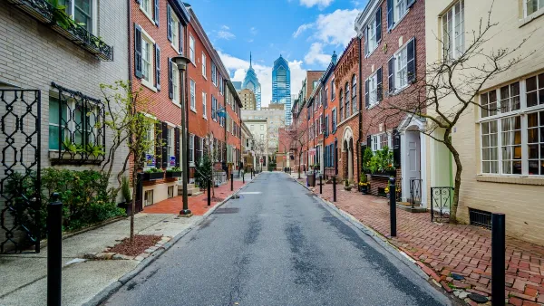Street with old buildings in Philadelphia, Pennsylvania and modern high-rise buildings in background.