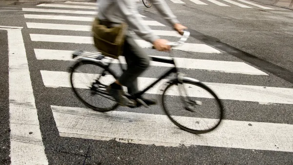 Person on bike riding across zebra crosswalk in city.