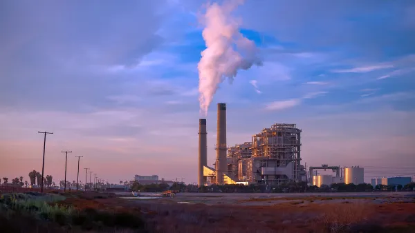 Natural gas power plant with two tall smokestacks against blue and purple sunset sky