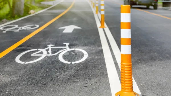 Bike lane delineated with white paint and orange bollards.