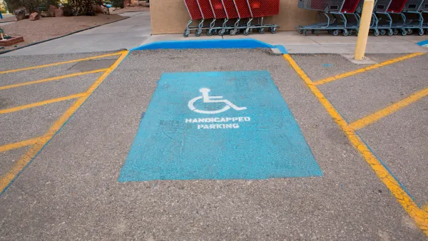 A handicap parking space with yellow painted wheelchair symbol and yellow hatched space on both sides.