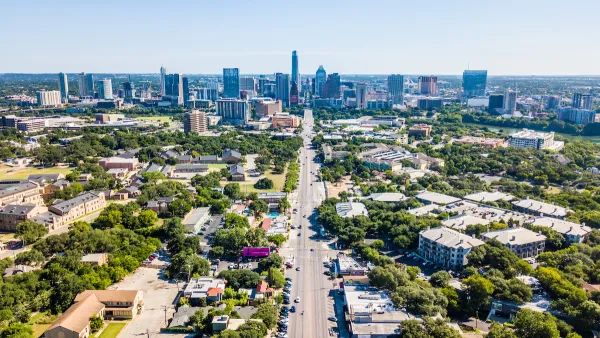 Aerial view of downtown Austin, Texas with state capitol dome at end of long, straight boulevard.