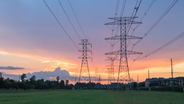 Electricity towers against sunset sky with green trees in background.
