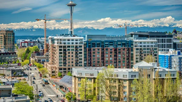 View of multistory buildings under construction in downtown Seattle, Washington with Space Needle and Mount Rainier in background.