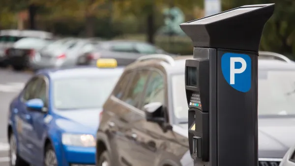 Parking payment machine on street with blurred cars parked in background.
