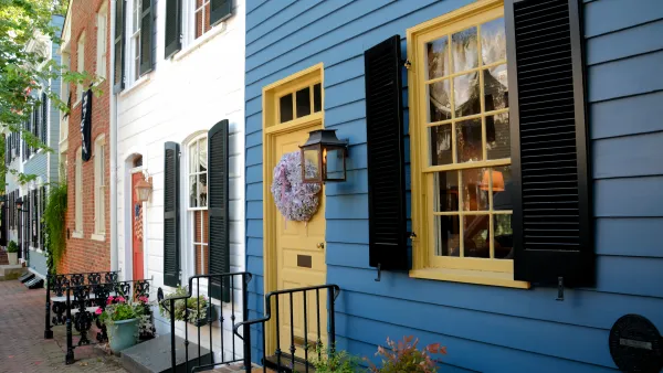 Line of blue, white, and red brick row homes with colorful doors and iron railings.