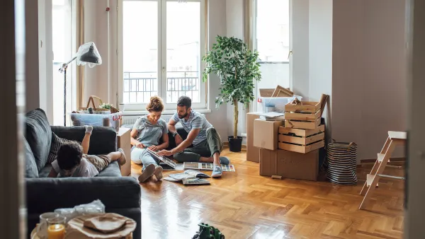 Man, woman, and child in apartment with moving boxes and crates.