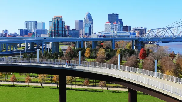 Skyline of Louisville, Kentucky with pedestrian walkway in foreground and vehicle bridge.