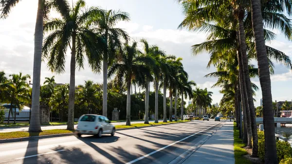View of palm tree-lined boulevard in Miami, Florida with white PT Cruiser driving by.
