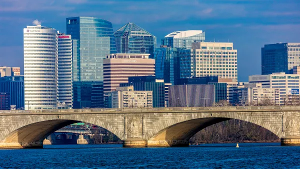 Washington D.C. office buildings with river and stone arched bridge in foreground.