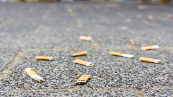 Flattened cigarette butts littering a sidewalk