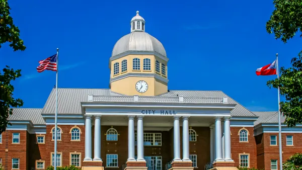 Neoclassical city hall building with dome, columns, and American flags flying in front
