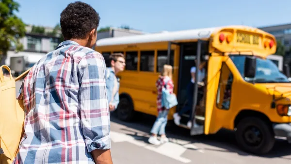 Children walking toward yellow school bus on a sunny day.
