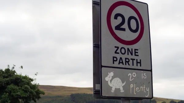 Close-up of white 20 kph speed limit sign in Europe with cartoon turtle and '20 is plenty' sticker underneath.