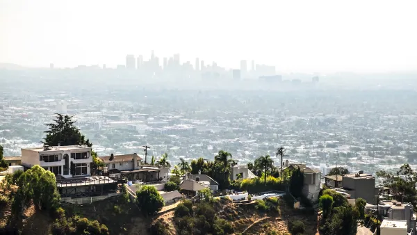 View of large mansions in Hollywood hills with downtown Los Angeles skyline in background.
