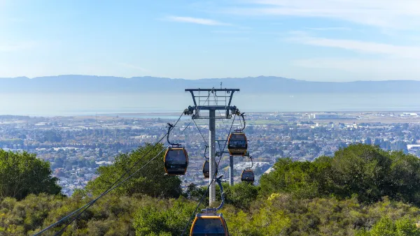 View of aerial tram cars at Oakland Zoo with Oakland, California neighborhoods in background.