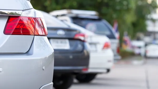 A view of the rear of four cars parked in angled spaces.
