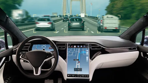 Interior of autonomous car with large map screen on road.