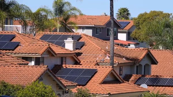 Photovoltaic solar panels on red-tile rooftops in California neighborhood.