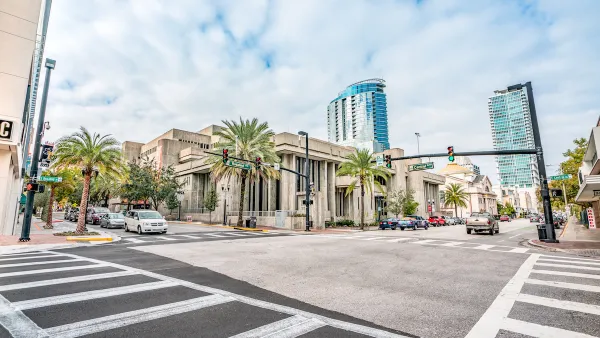 View of empty zebra crosswalk at intersection in Orlando, Florida with glass towers in background.