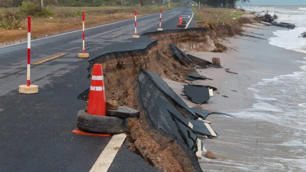 Asphalt road on coast with collapsed segments from erosion.