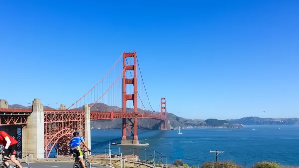Two cyclists on a paved bike path overlooking the Golden Gate Bridge, San Francisco, California.