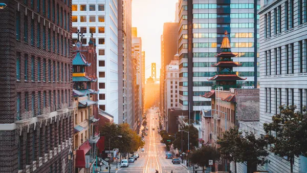 View down California Street in San Francisco, California with Chinatown pagoda buildings and golden hour sky in background.