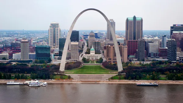 View of the Gateway Arch with Mississippi River in foreground and St. Louis skyline in background.