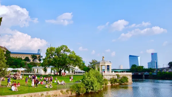 Riverfront park in Philadelphia with white gazebo and skyscrapers in background.