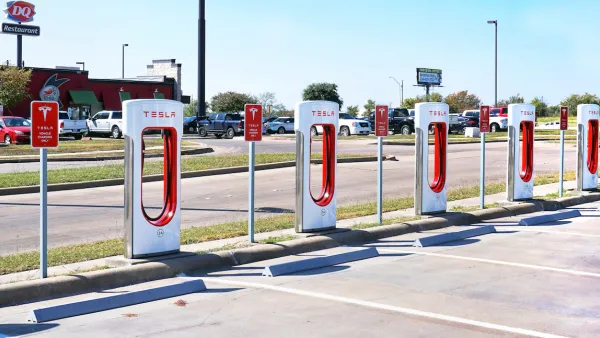 White and red Tesla EV chargers in an open-air parking lot in Corsicana, Texas with Dairy Queen restaurant in background