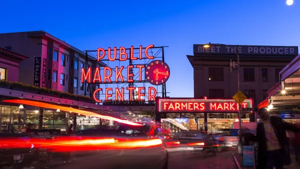 Pike Place Market in Seattle at twilight with neon market sign and cars passing through.